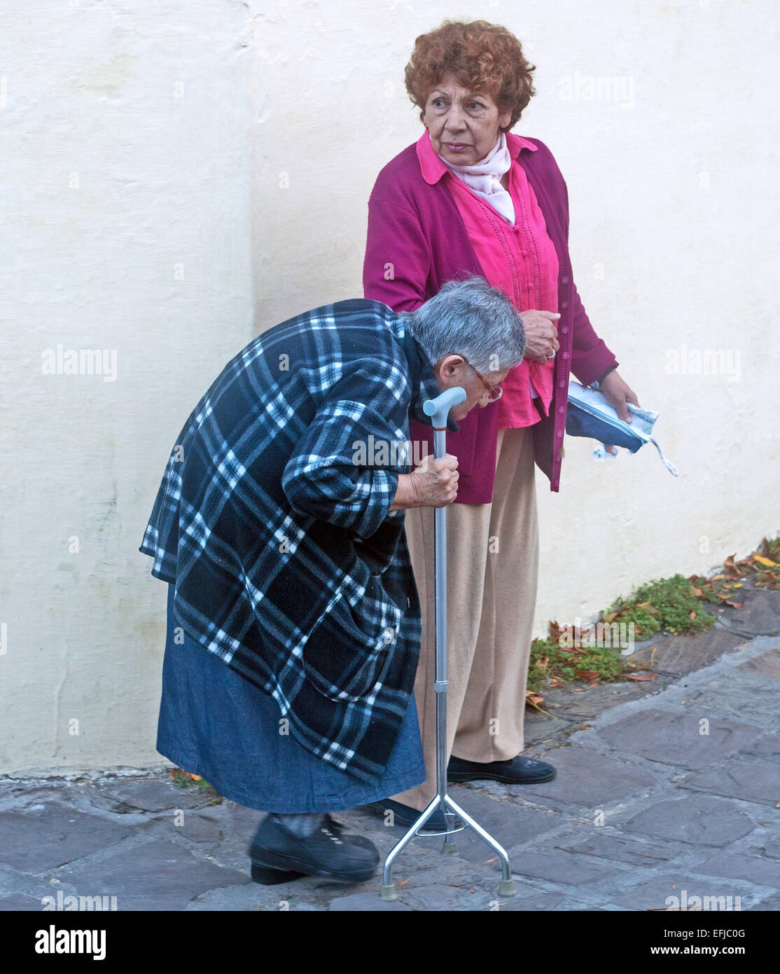 Frau, unterstützen eine ältere Dame mit Krümmung der Wirbelsäule zu Fuß mit ihrem Krücke Jujuy, Argentinien Stockfoto