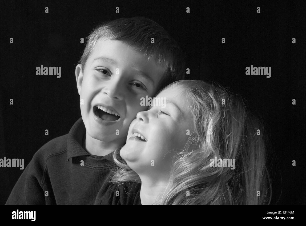 Schwarz / weiß Porträt des jungen stören und Schwester lachen, isoliert auf schwarz Stockfoto