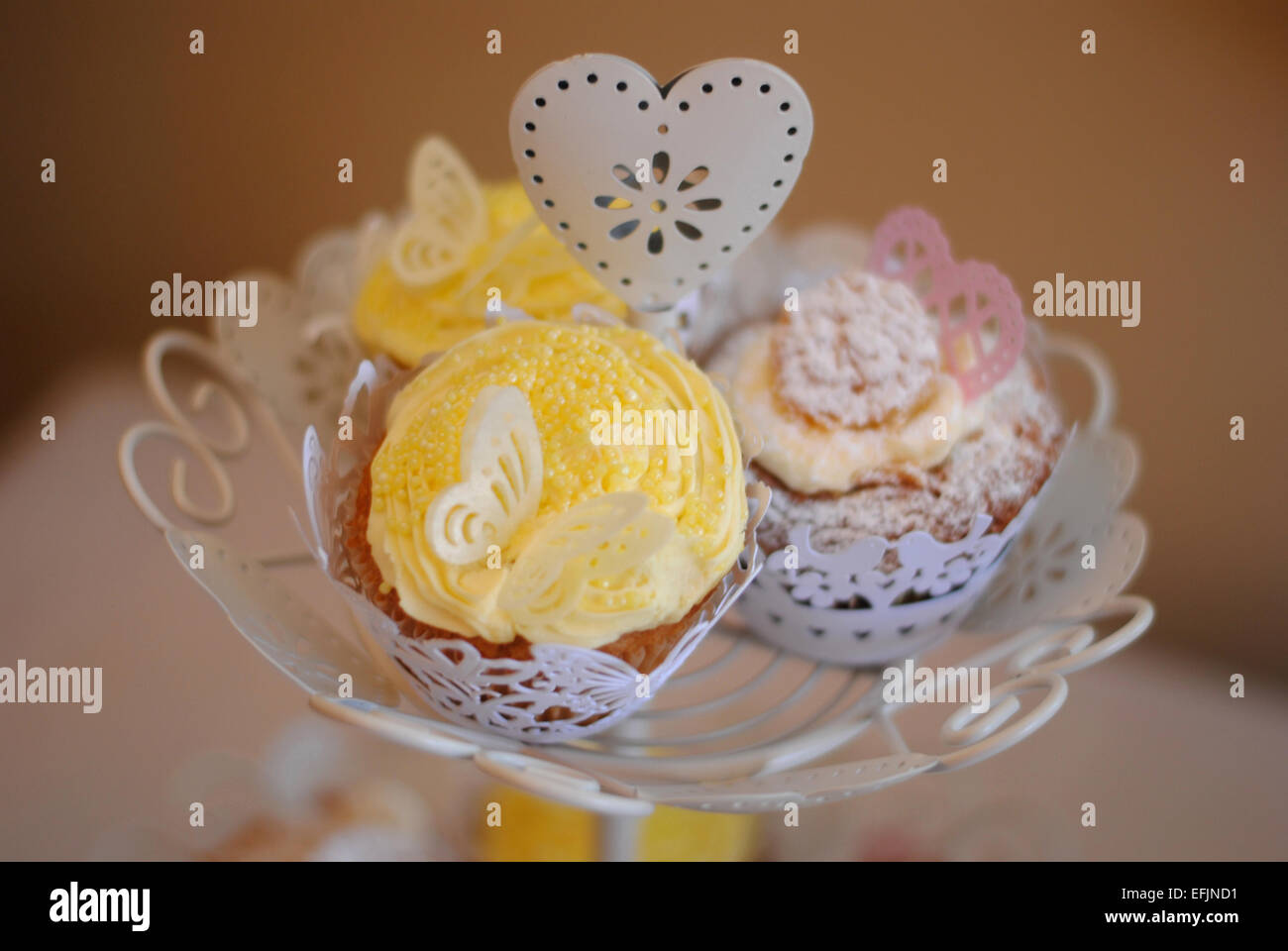 Drei hausgemachte Schmetterling-Muffins auf einem weißen shabby chic Kuchen stehen Stockfoto