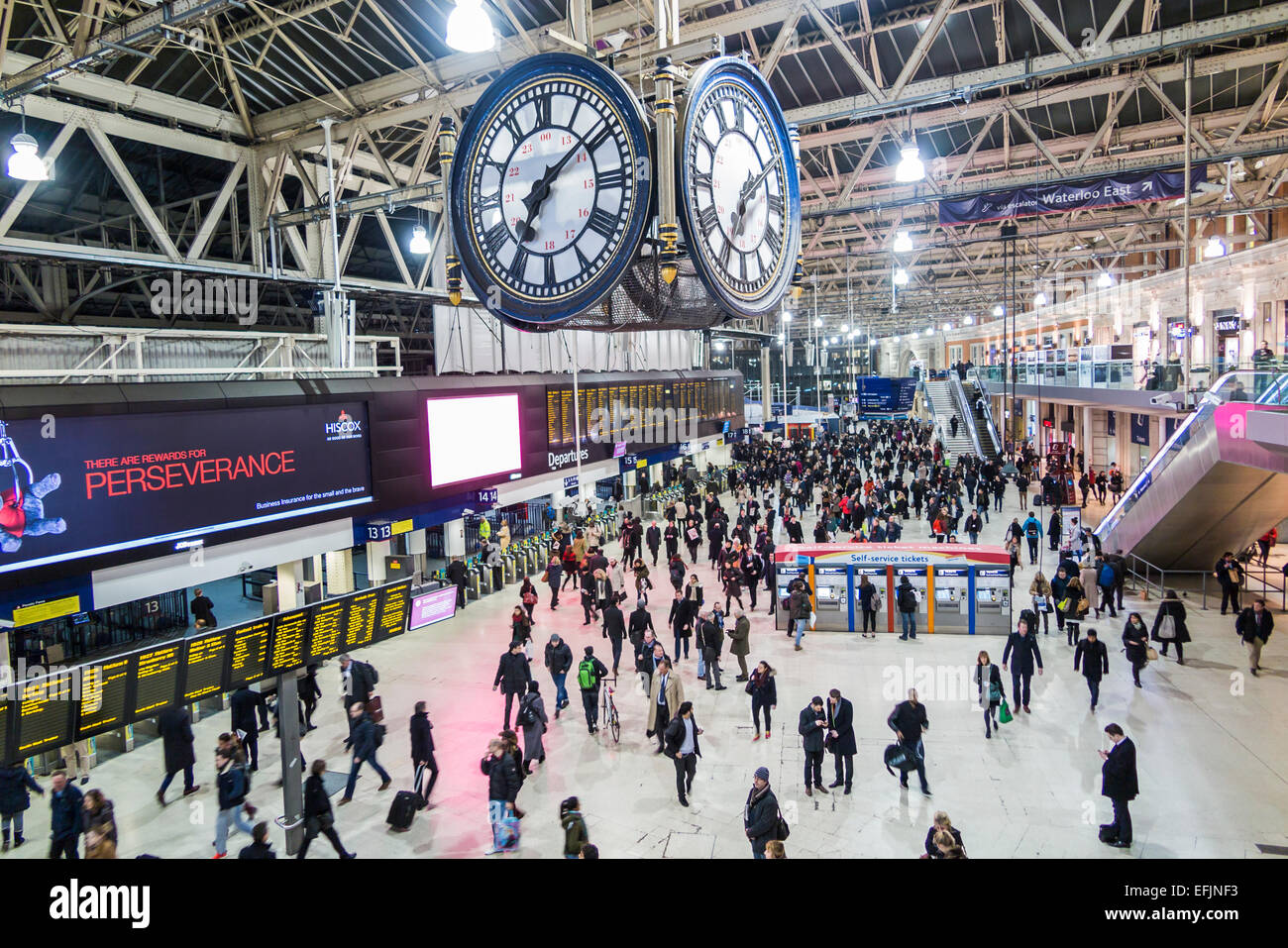 London Waterloo Bahnhofsuhr und Concourse, überlaufen mit abendlichen Hauptverkehrszeit Pendler durch die Schilder unter der Uhr Stockfoto
