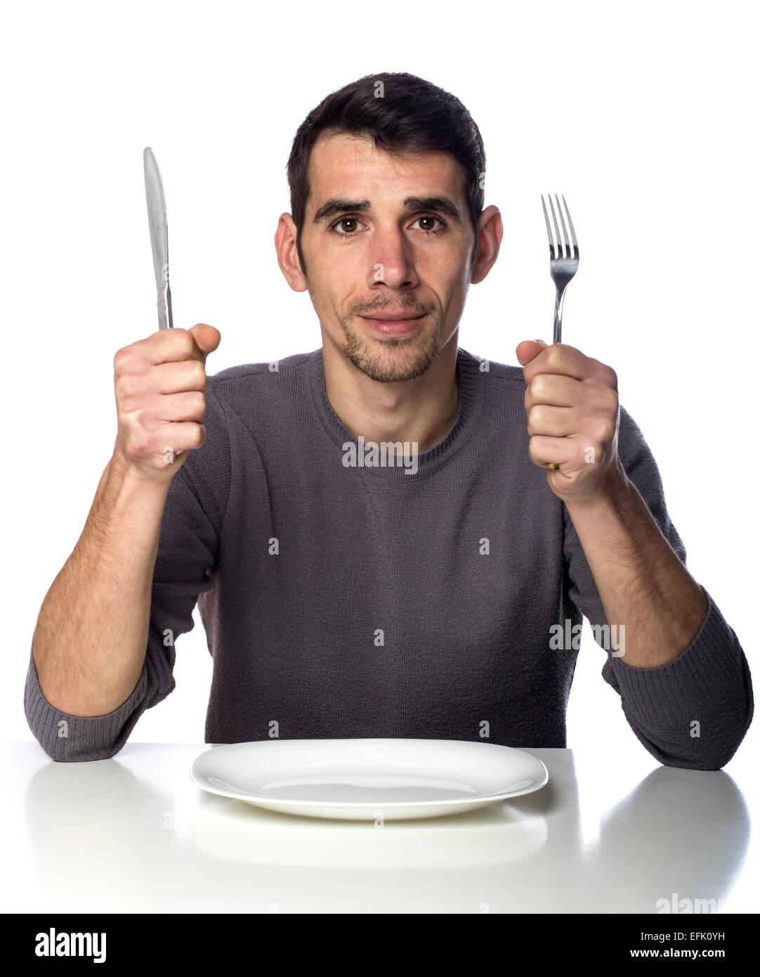 Mann am Tisch mit Gabel und Messer angehoben. Hungerstreik isoliert auf weißem Hintergrund Stockfoto
