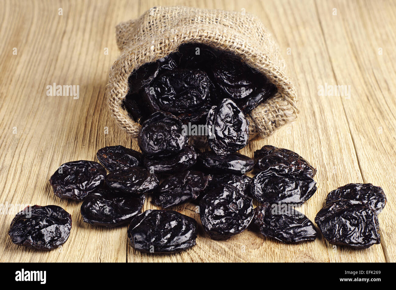 Getrocknete Pflaumen in kleine Sack auf Holztisch Stockfoto