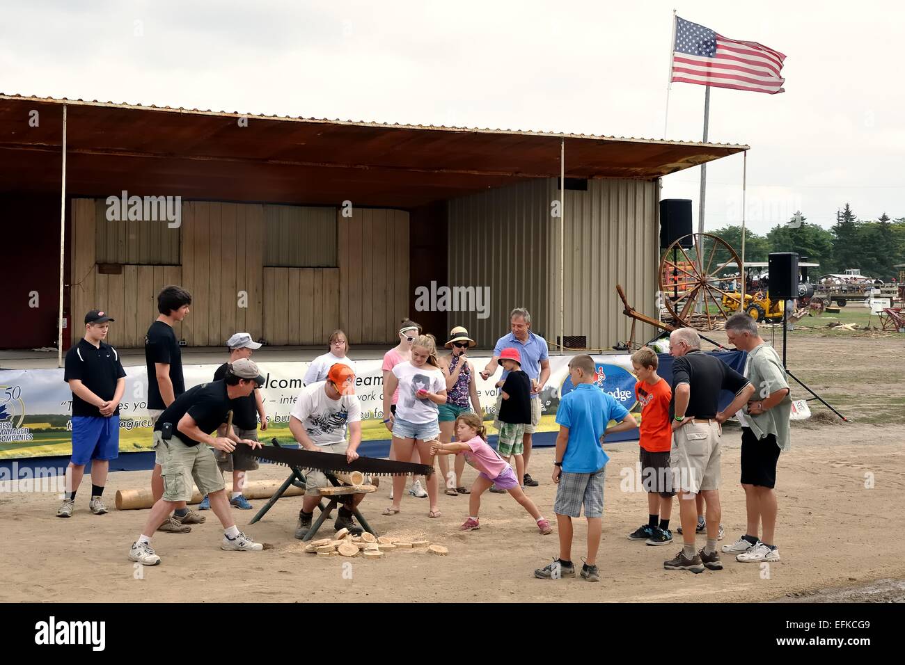Eine Gruppe von Menschen lernen, wie man eine zwei-Mann-Ablängsäge zu verwenden, auf der "Dampf und Traktor" in Milton, Ontario, Kanada Stockfoto