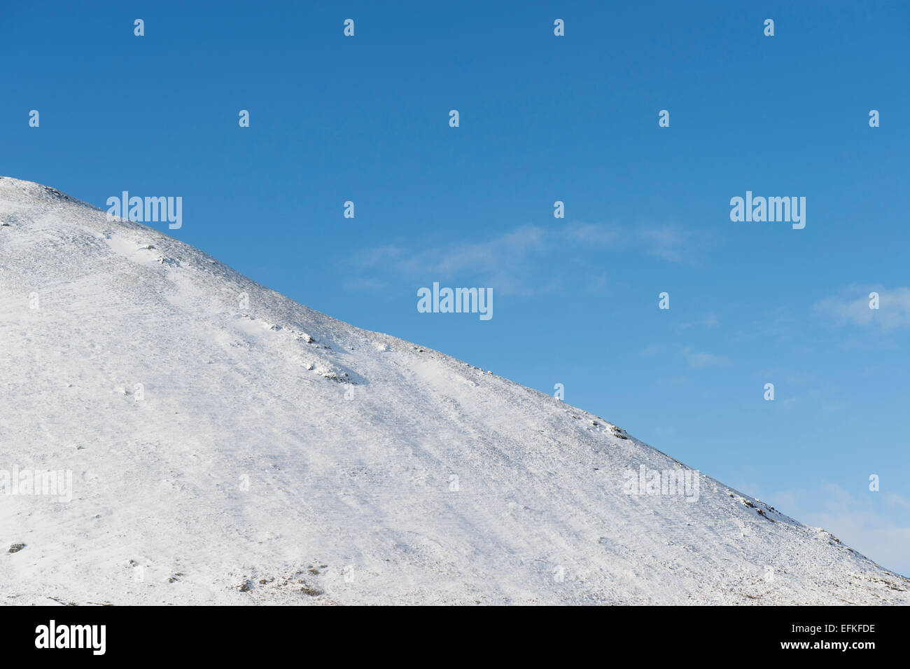 Berghang im Schnee mit blauem Himmel bedeckt. Scottish Borders, Schottland Stockfoto