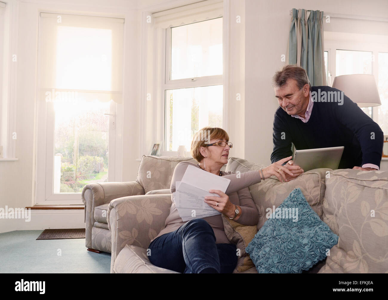Älteres Paar zu Hause betrachten von Dokumenten und digitalen tablet Stockfoto