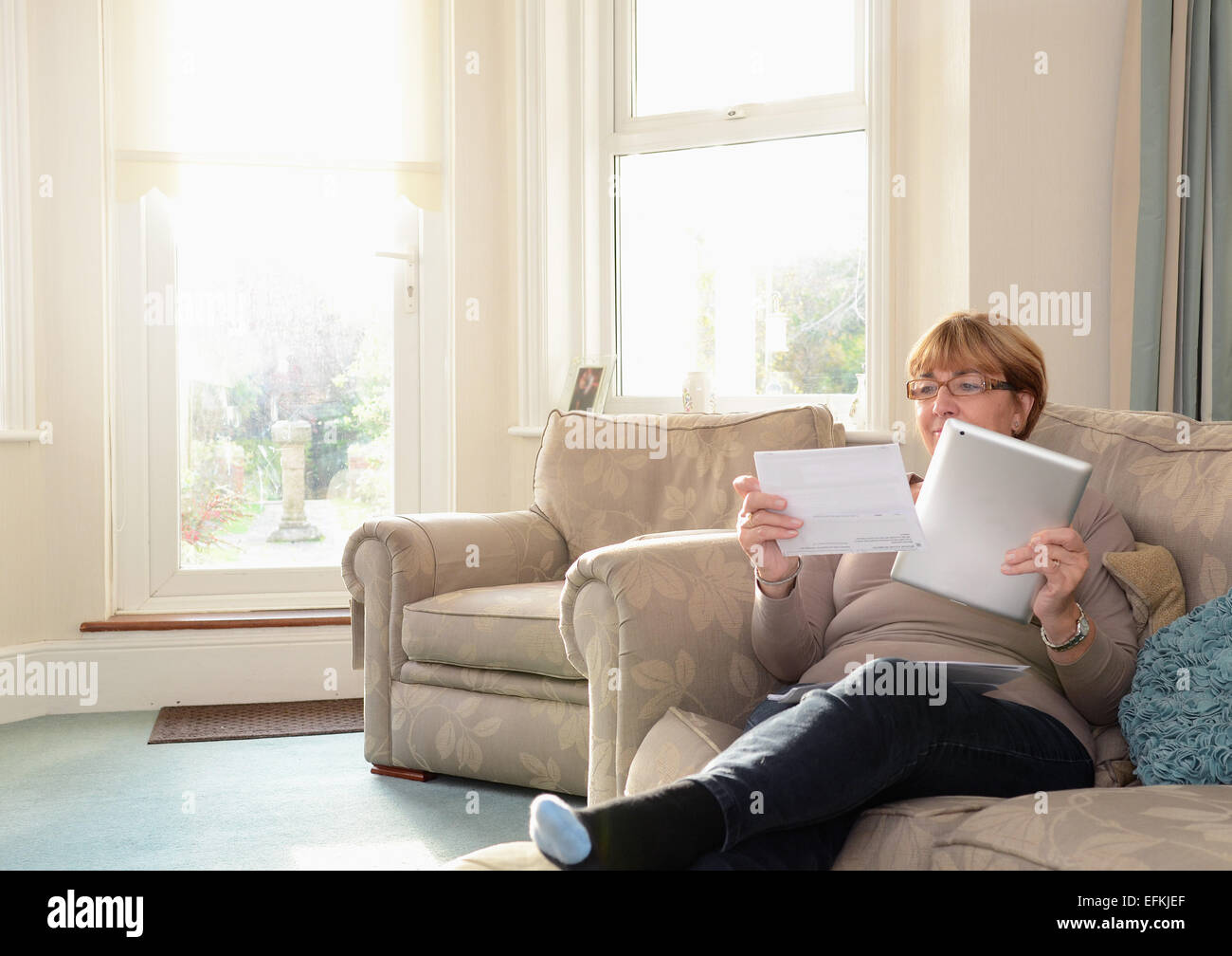 Ältere Frau auf Sofa mit digital-Tablette Stockfoto