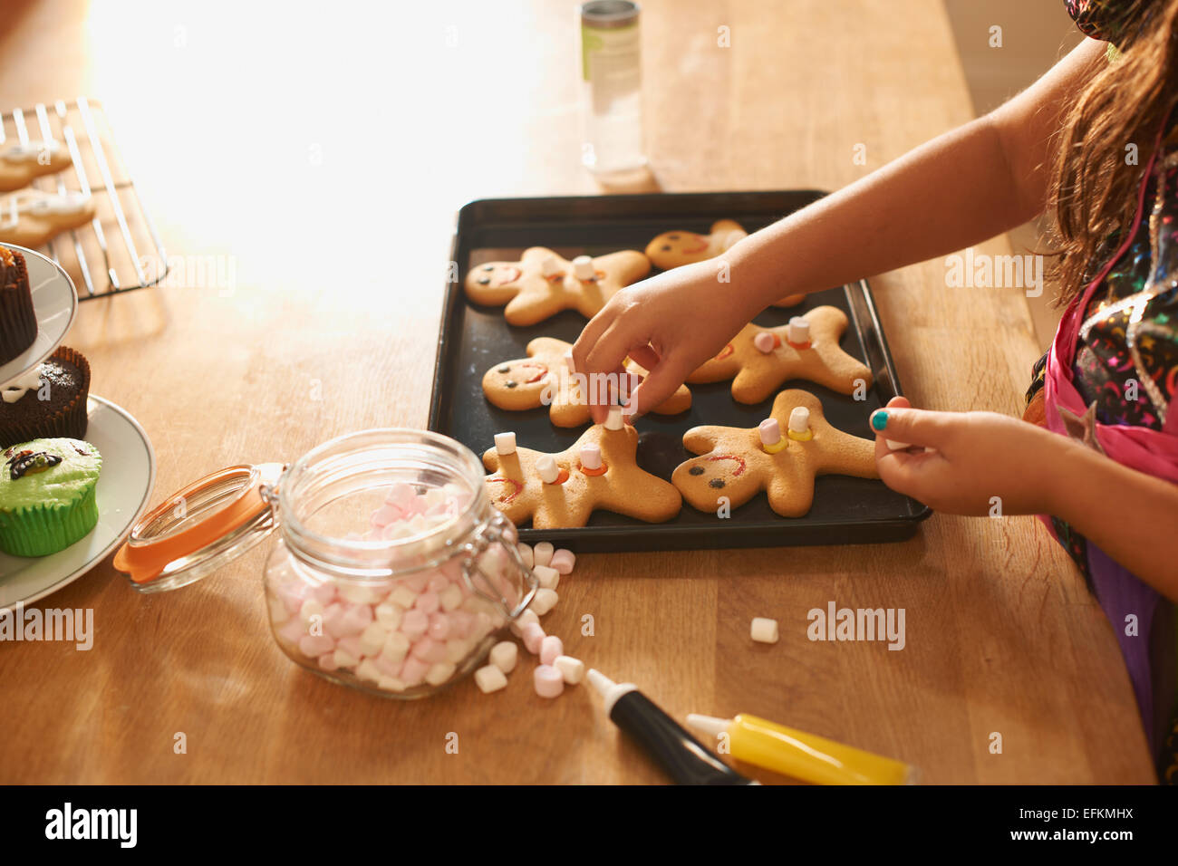 Händen der Mädchen in der Küche Lebkuchenmänner für Halloween Dekoration Stockfoto