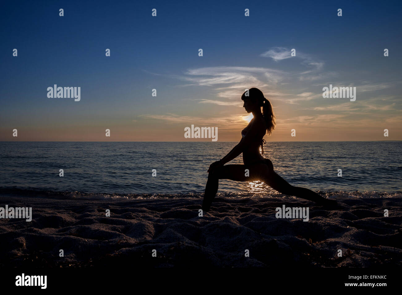 Silhouette junge Frau praktizieren Yoga bei Sonnenuntergang, Oristano, Sardinien, Italien Stockfoto
