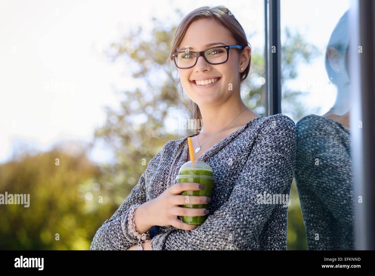 Porträt der jungen Frau mit Kaffee zum Mitnehmen gelehnt Parkbau Stockfoto