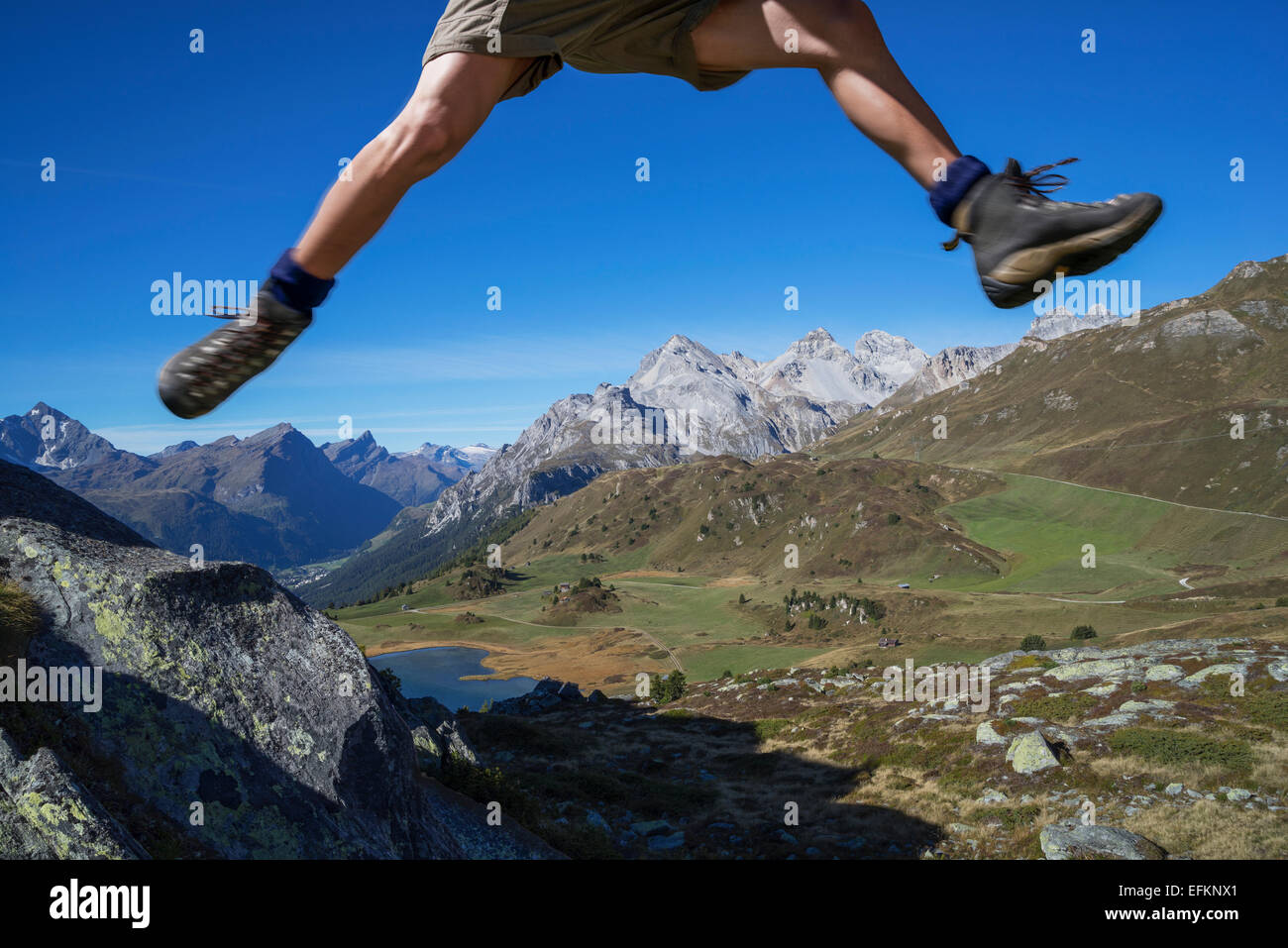 Beine des männlichen Wanderer springen über Felsen, Lai da Fons, Kanton Graubünden, Schweiz Stockfoto