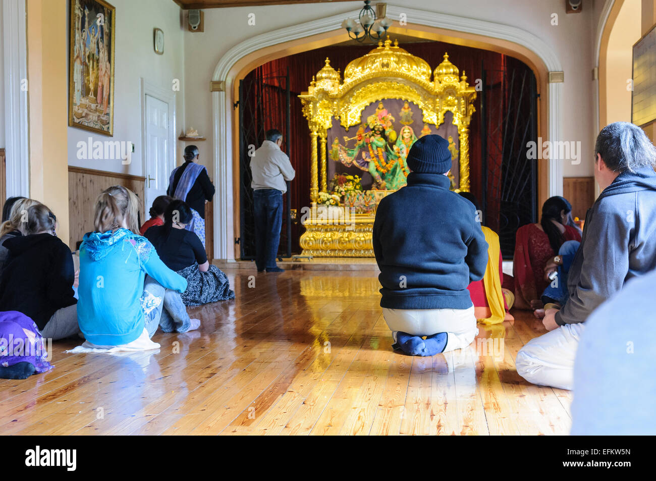 Anzahl der Personen kniend und betend an einem Hare Krishna altar Stockfoto