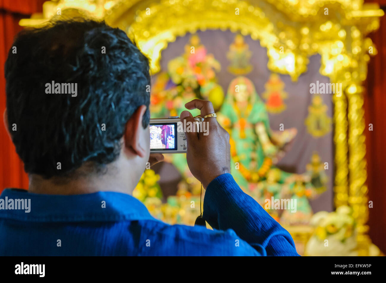 Ein Mann nimmt ein Foto von einem Hare Krishna goldenen Altar, Lord Vishnu eine Stockfoto