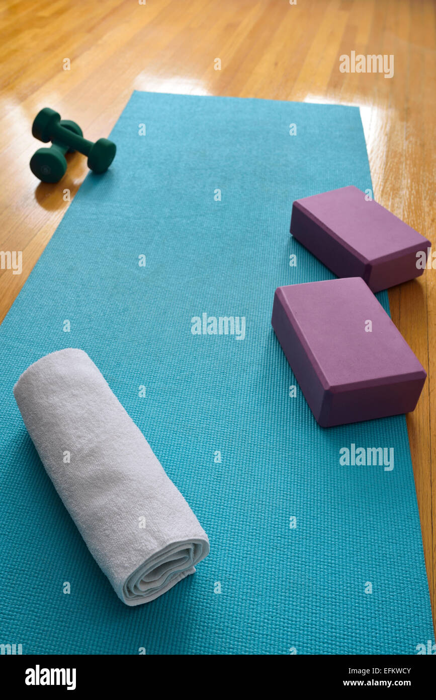 Blaue Yogamatte Übung im Fitness-Studio mit Eiche Boden und Handtuch Hanteln und Blöcke Stockfoto