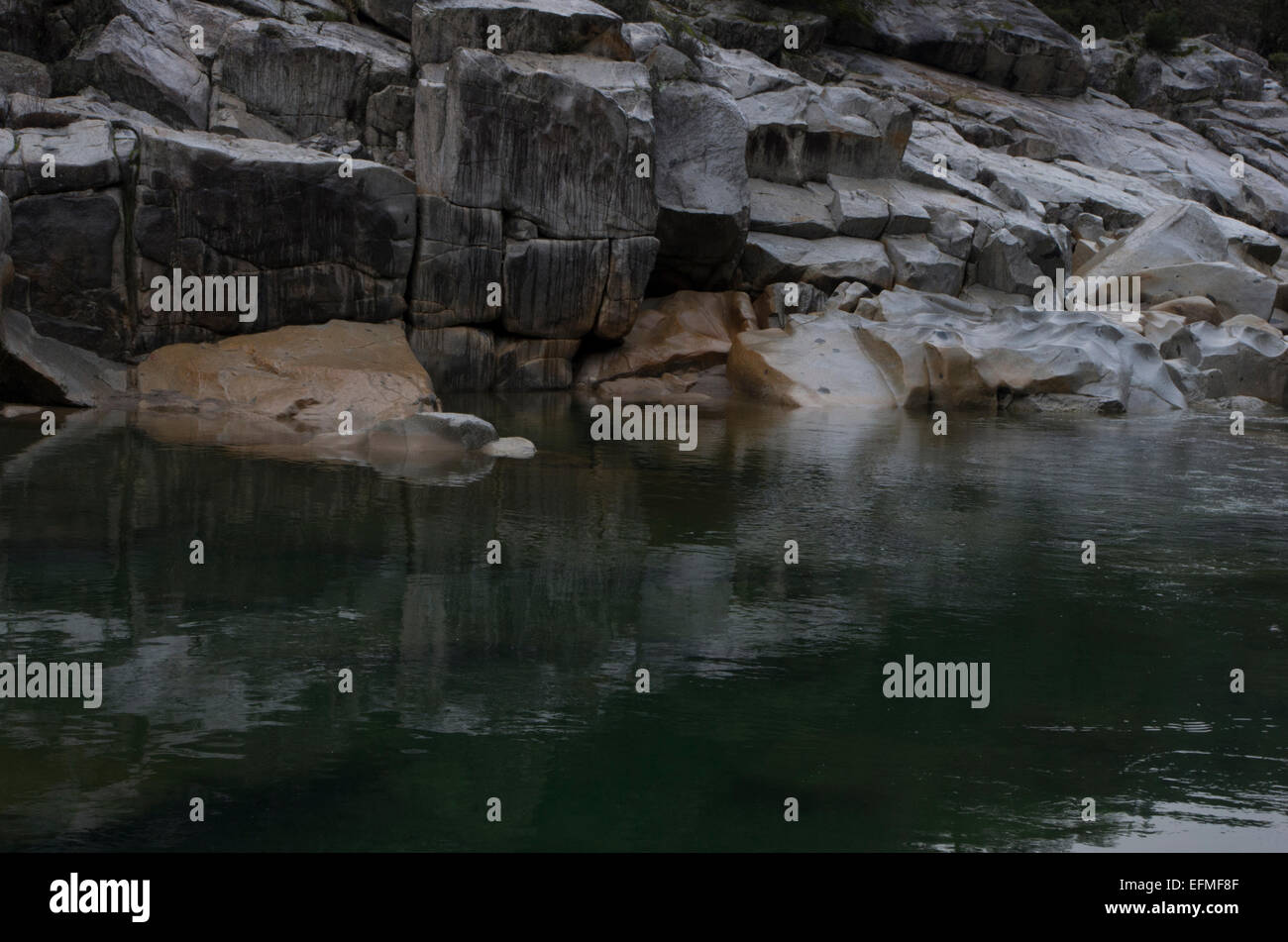Granit-Gesicht trifft Oberfläche des Flusses Stockfoto