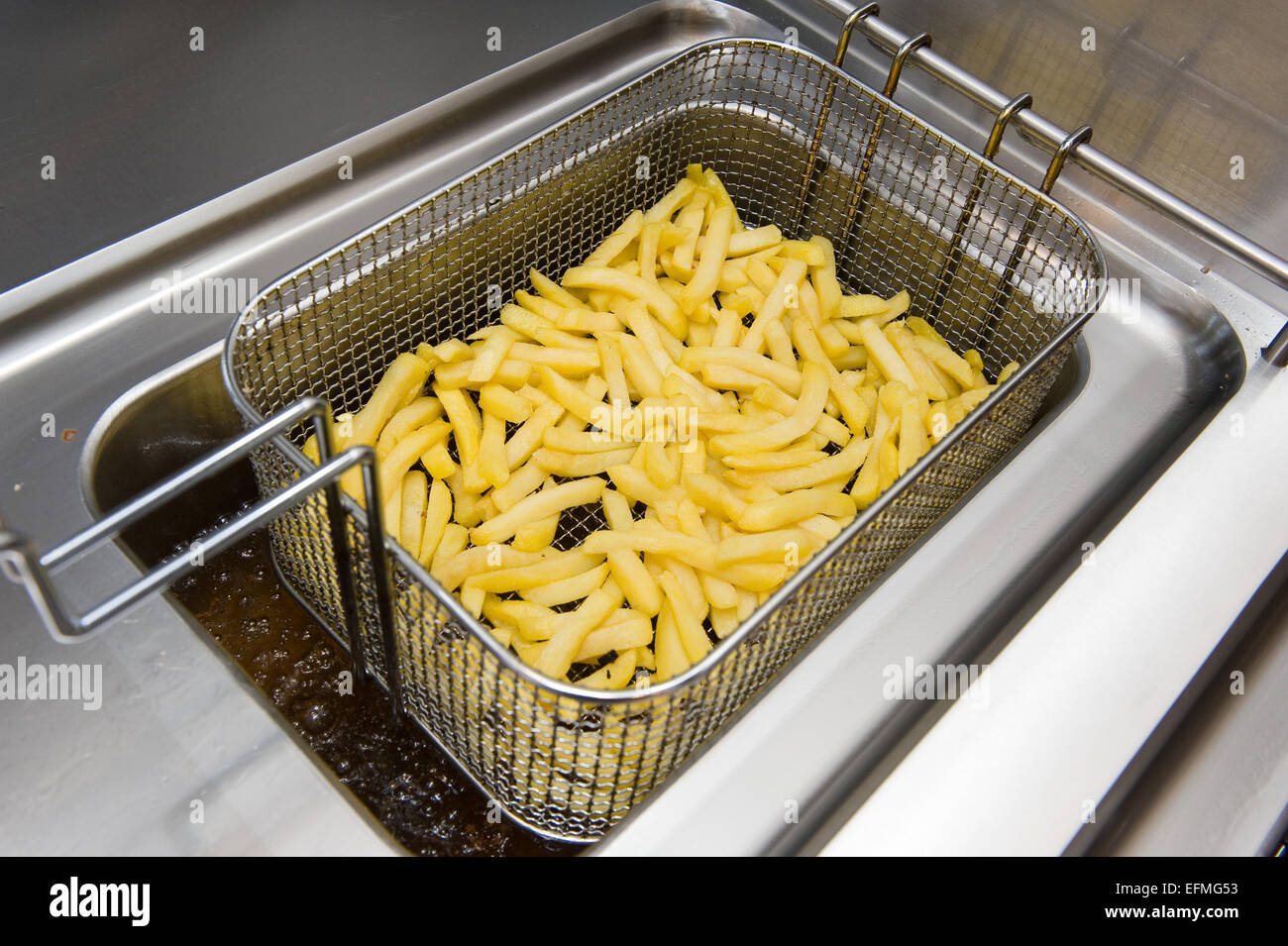 Pommes-frites-Backen in Fett in einer Cafeteria Stockfoto