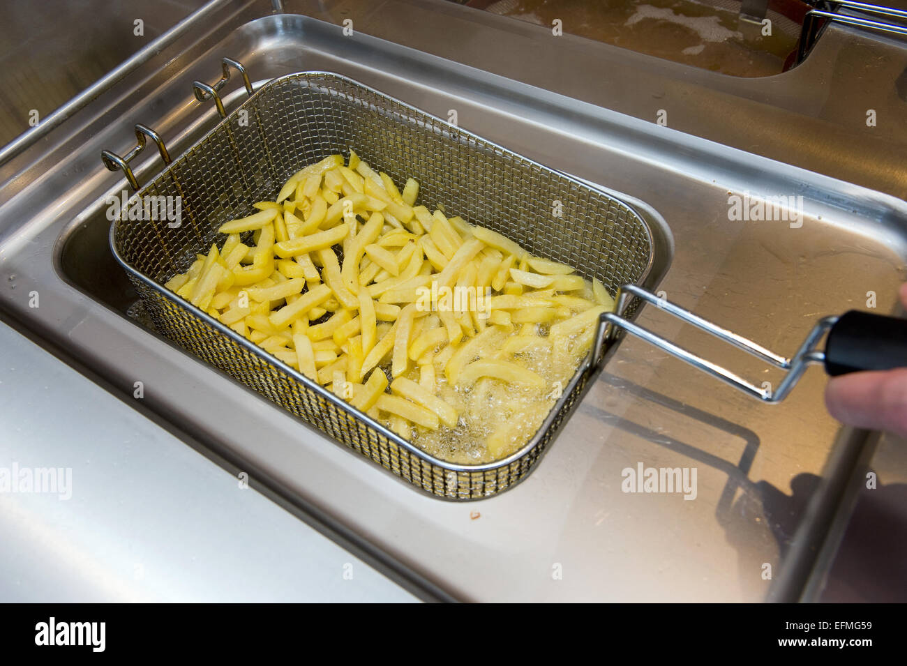 Pommes-frites-Backen in Fett in einer Cafeteria Stockfoto