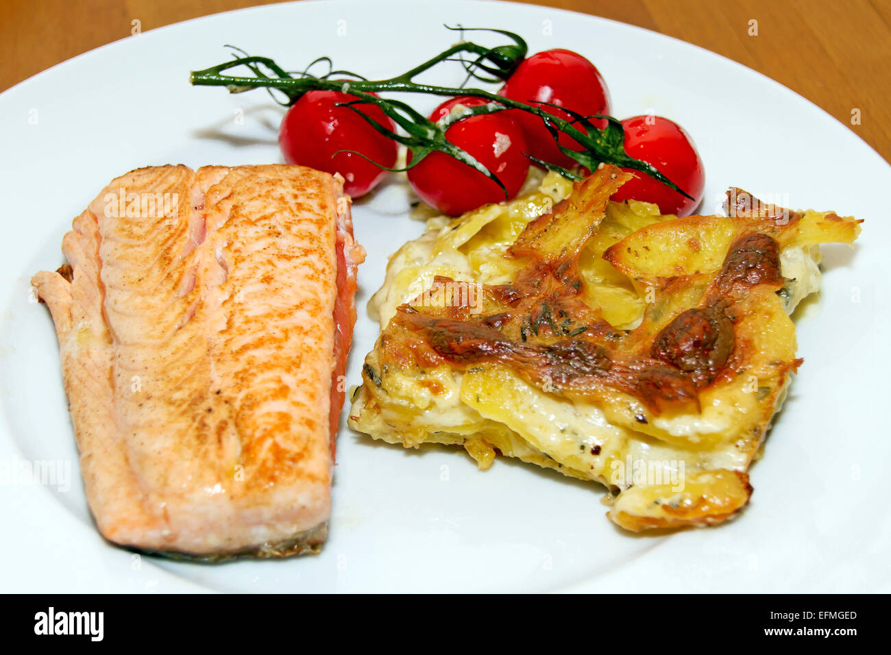 Lachs mit Kartoffel-Gratin und Cherry-Tomaten Stockfoto