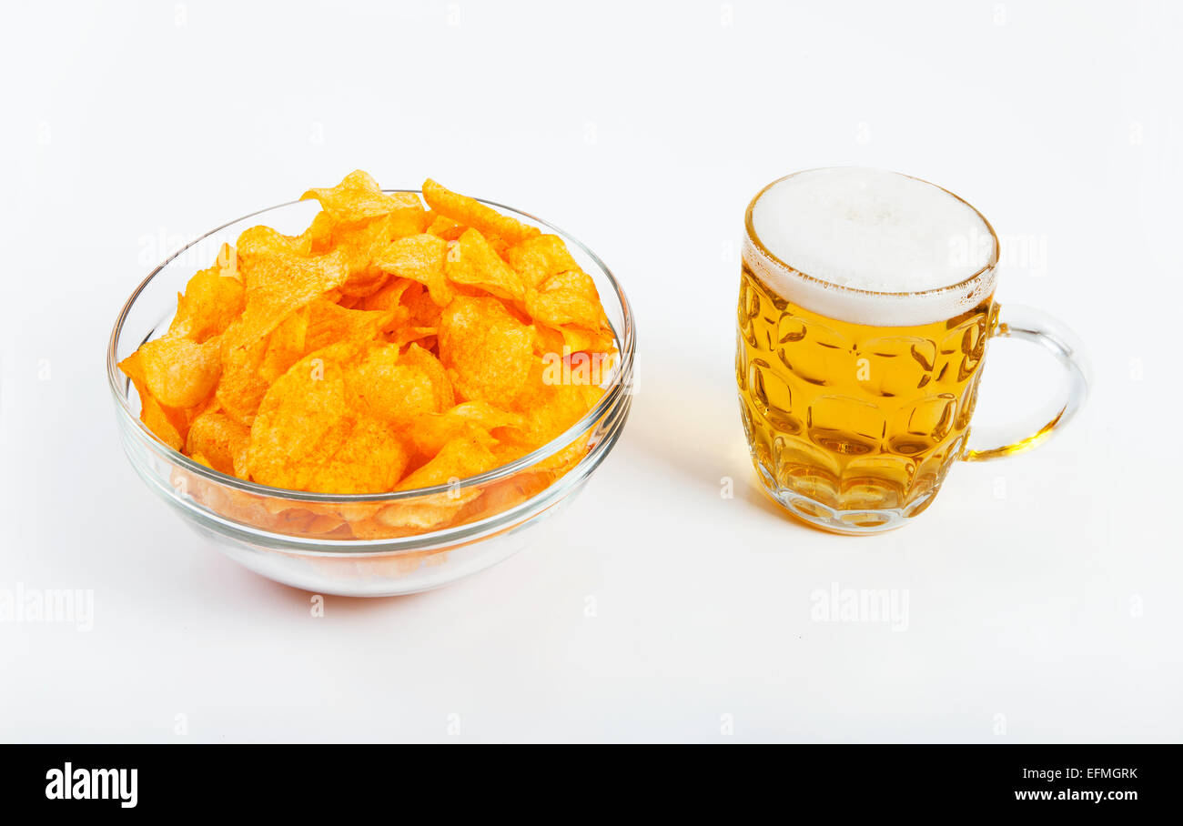 eine Glasschüssel gefüllt mit Kartoffel-Chips und ein Glas Bier vor weißem Hintergrund Stockfoto