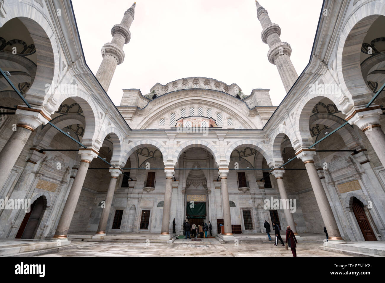 Nuruosmaniye Moschee Innenhof Kolonnade Istanbul // ISTANBUL, Türkei — die halbrunde Kolonnade rund um den Innenhof der Nuruosmaniye Moschee zeigt das innovative hufeisenförmige Design, das eine Abkehr von der traditionellen osmanischen Architektur markiert. 1755 unter Sultan Osman III. Fertiggestellt, war dies der erste nicht rechteckige Moscheehof in der osmanischen Architekturgeschichte. Die geschwungene Kolonnade veranschaulicht den osmanischen Barockstil, der Mitte des 18. Jahrhunderts entstand und europäische architektonische Elemente mit islamischen Gestaltungsprinzipien verbindet. Die Nuruosmaniye-Moschee war die erste im Stockfoto
