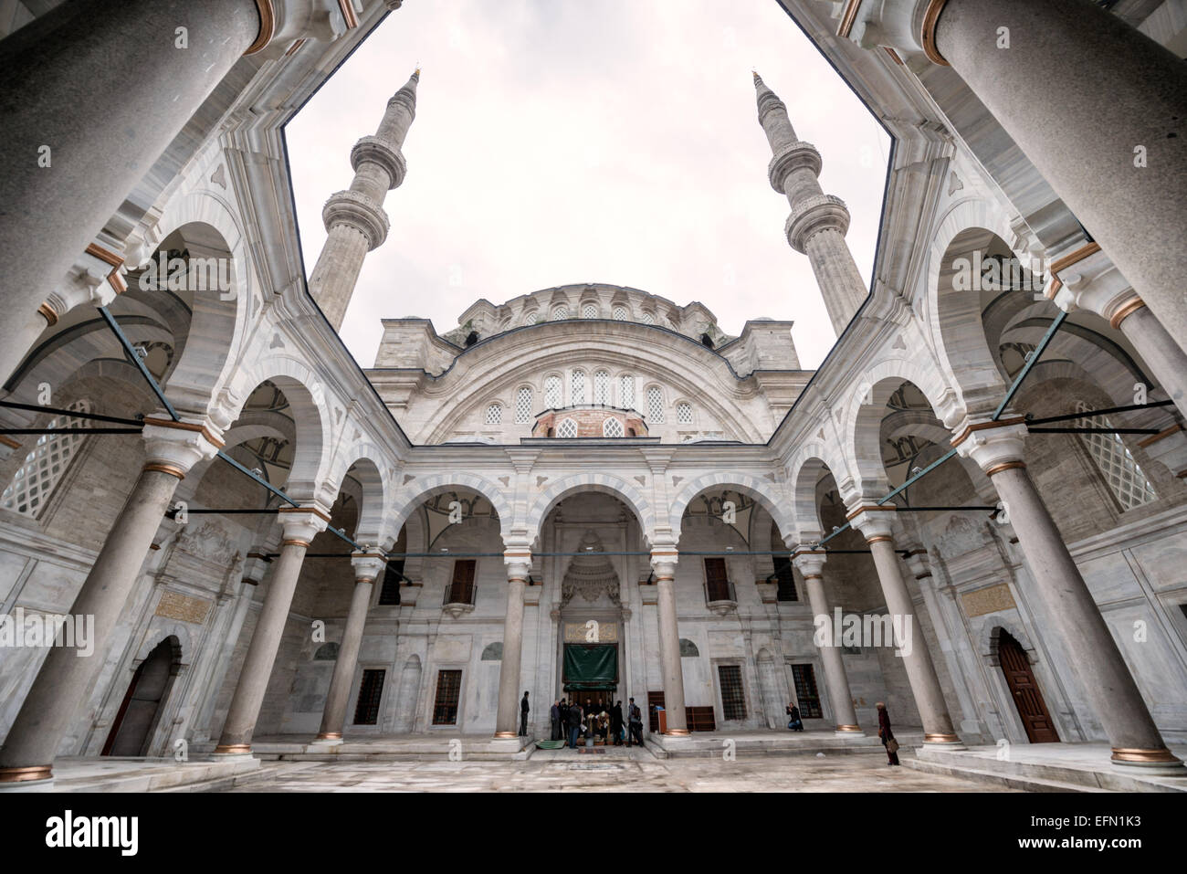 Nuruosmaniye Moschee Innenhof Kolonnade Istanbul // ISTANBUL, Türkei — die halbrunde Kolonnade rund um den Innenhof der Nuruosmaniye Moschee zeigt das innovative hufeisenförmige Design, das eine Abkehr von der traditionellen osmanischen Architektur markiert. 1755 unter Sultan Osman III. Fertiggestellt, war dies der erste nicht rechteckige Moscheehof in der osmanischen Architekturgeschichte. Die geschwungene Kolonnade veranschaulicht den osmanischen Barockstil, der Mitte des 18. Jahrhunderts entstand und europäische architektonische Elemente mit islamischen Gestaltungsprinzipien verbindet. Die Nuruosmaniye-Moschee war die erste im Stockfoto