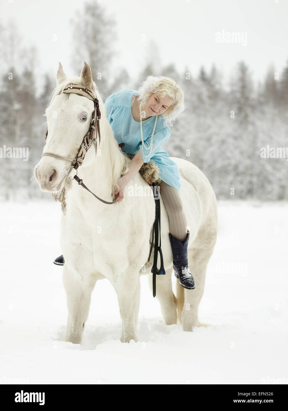 Attraktive Frau mit blauen Kleid und sie auf einem weißen Pferd Stockfoto