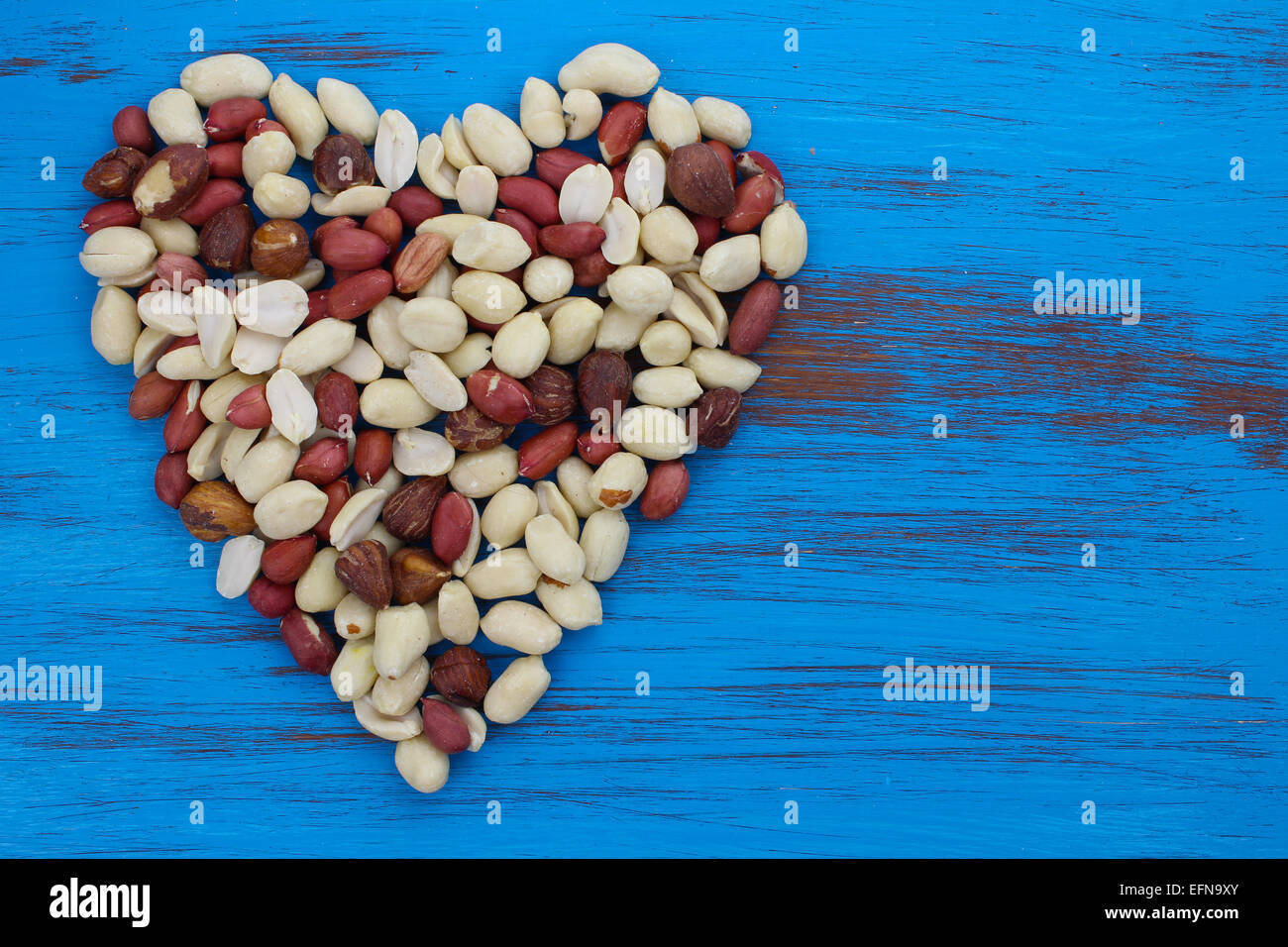 Erdnüsse-Muttern in Form eines Herzens auf blauem rustikale notleidenden Holz Hintergrund. Stockfoto