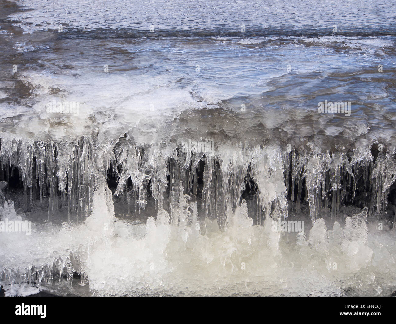 Kleiner Wasserfall oder Wehr, noch dekorativer im Winter teilweise gefroren, Eiszapfen und Miniatur-Höhlen, Alna, Oslo Norwegen Stockfoto