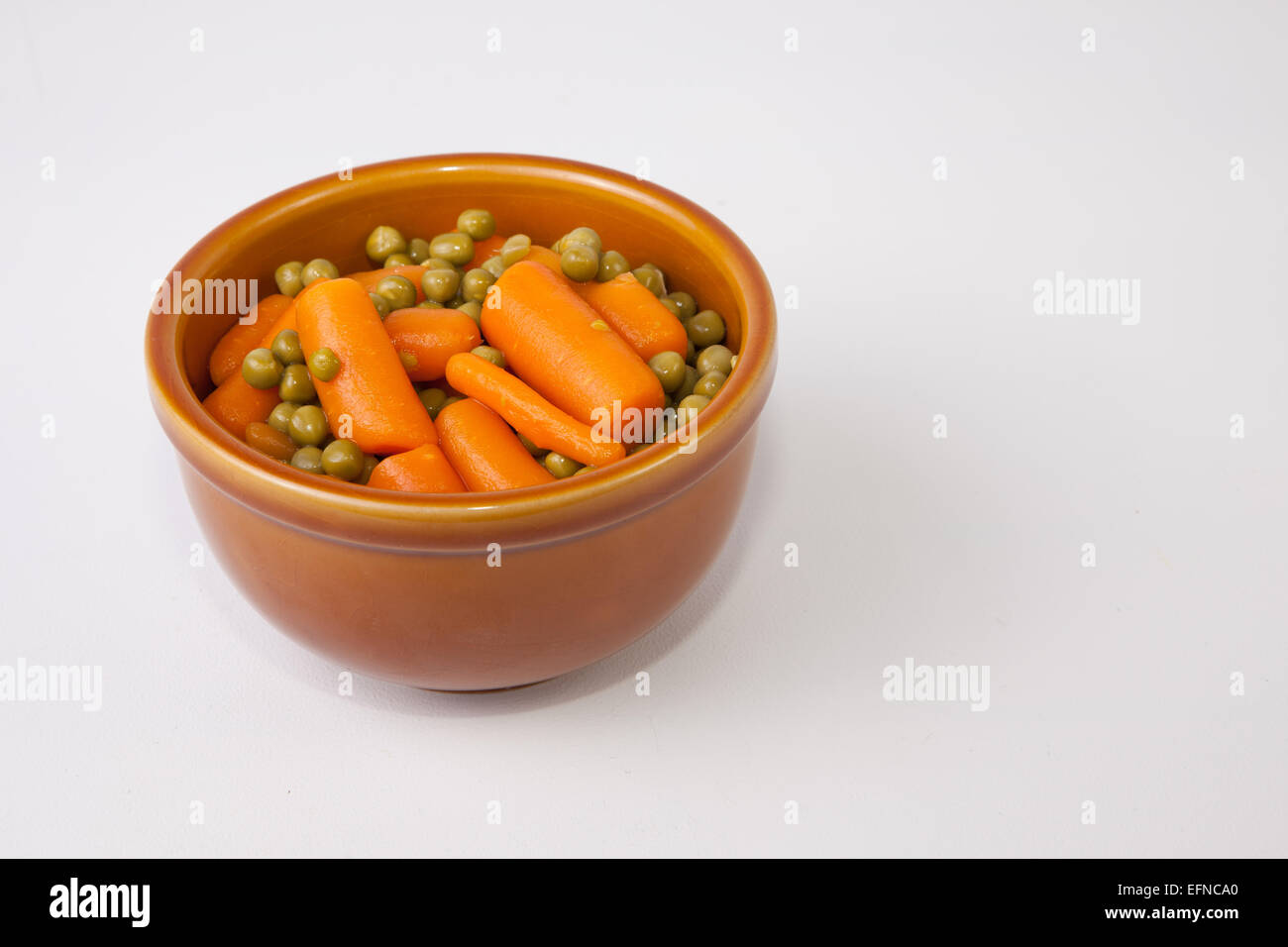 Gekochte Karotten und Erbsen auf rustikalen glasiertem Ton Schüssel. Isoliert auf weißem Hintergrund Stockfoto