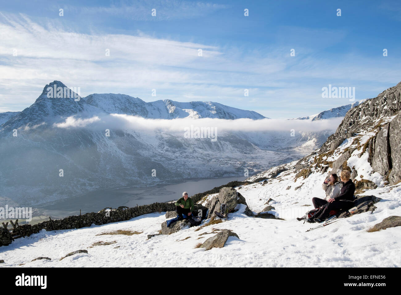Wanderer ruht auf Weg zu Carneddau Berge über Ogwen Valley mit Blick auf Mount Tryfan im Winter. Snowdonia National Park (Eryri) Wales UK Großbritannien Stockfoto
