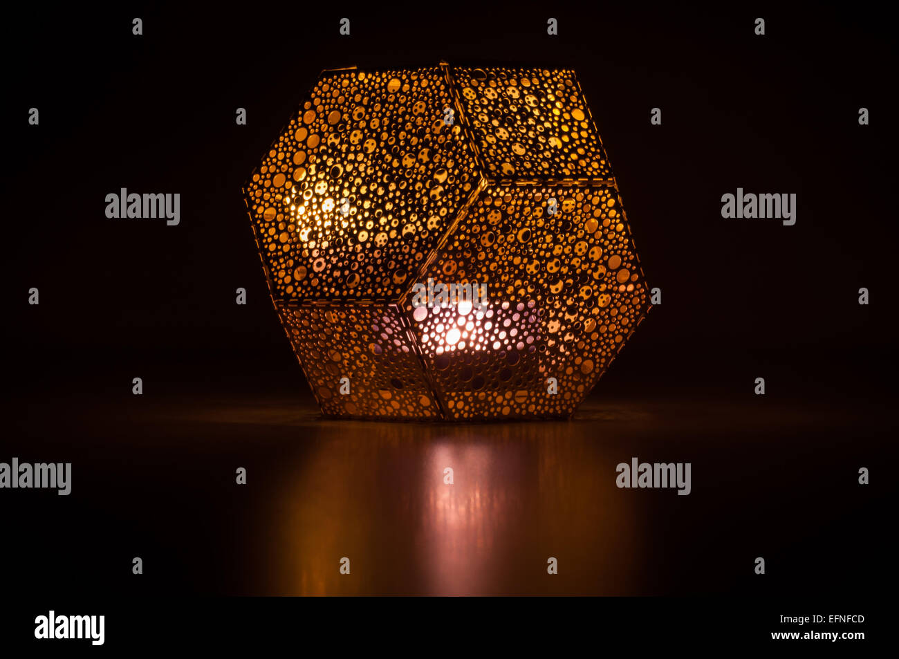 Dixon golden Sechskant-Kerze-Halter mit einer brennenden Kerze Stockfoto