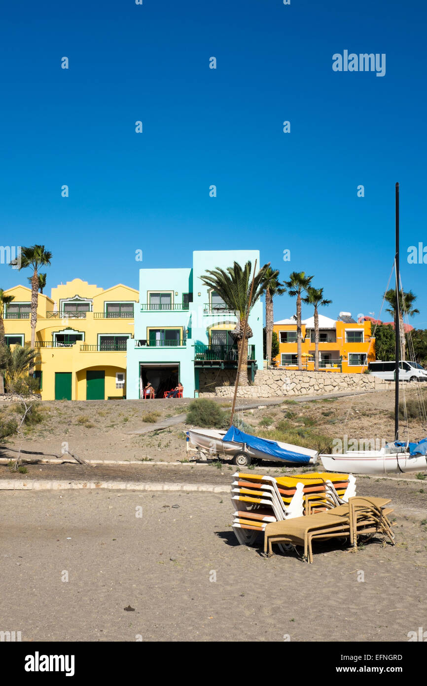 Unbenutzte Liegestühle am Strand vor bunten Ferienhäuser, El Medano, Teneriffa Stockfoto