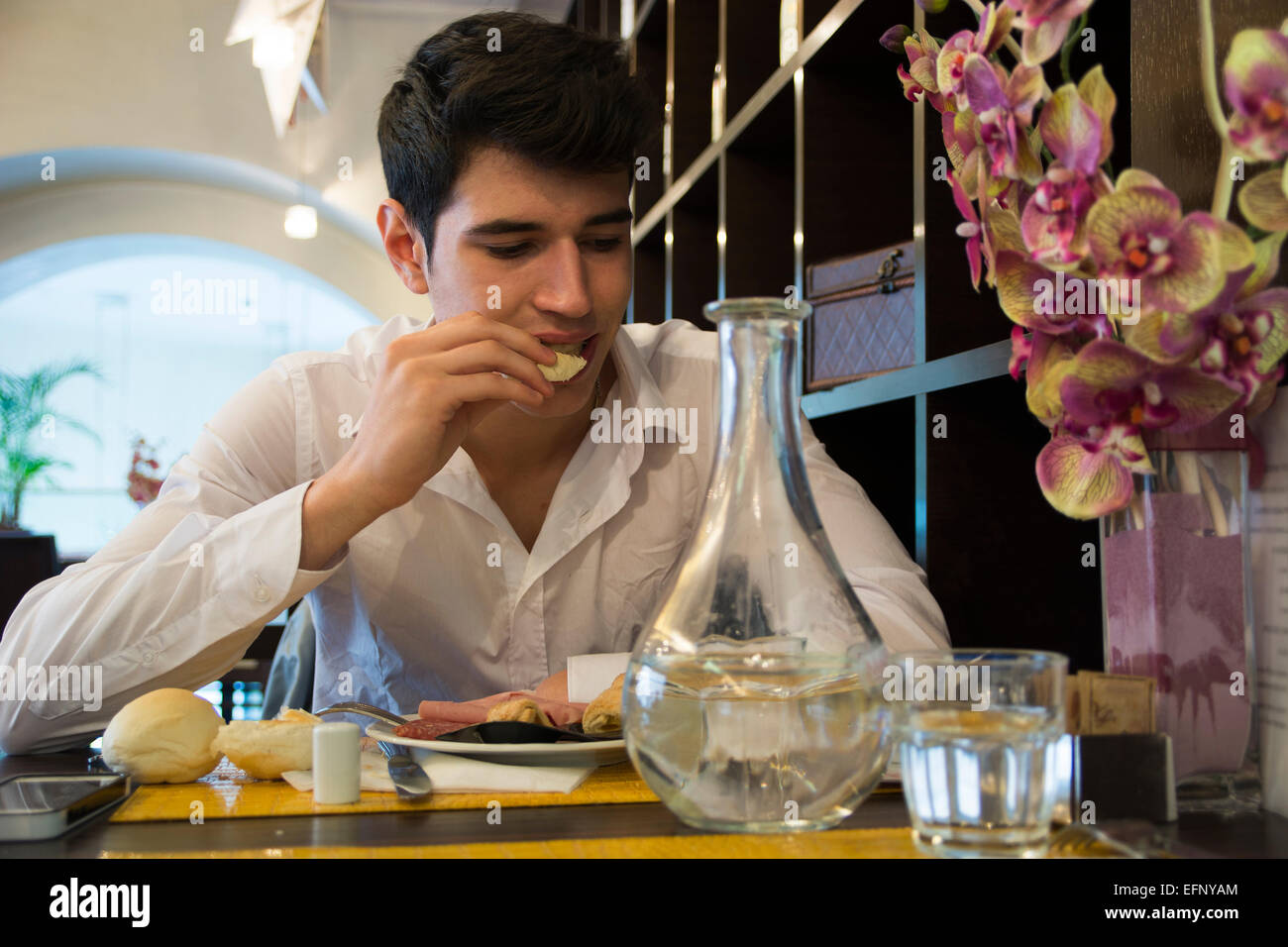 Attraktive junge Mann im eleganten Restaurant Essen Stockfoto