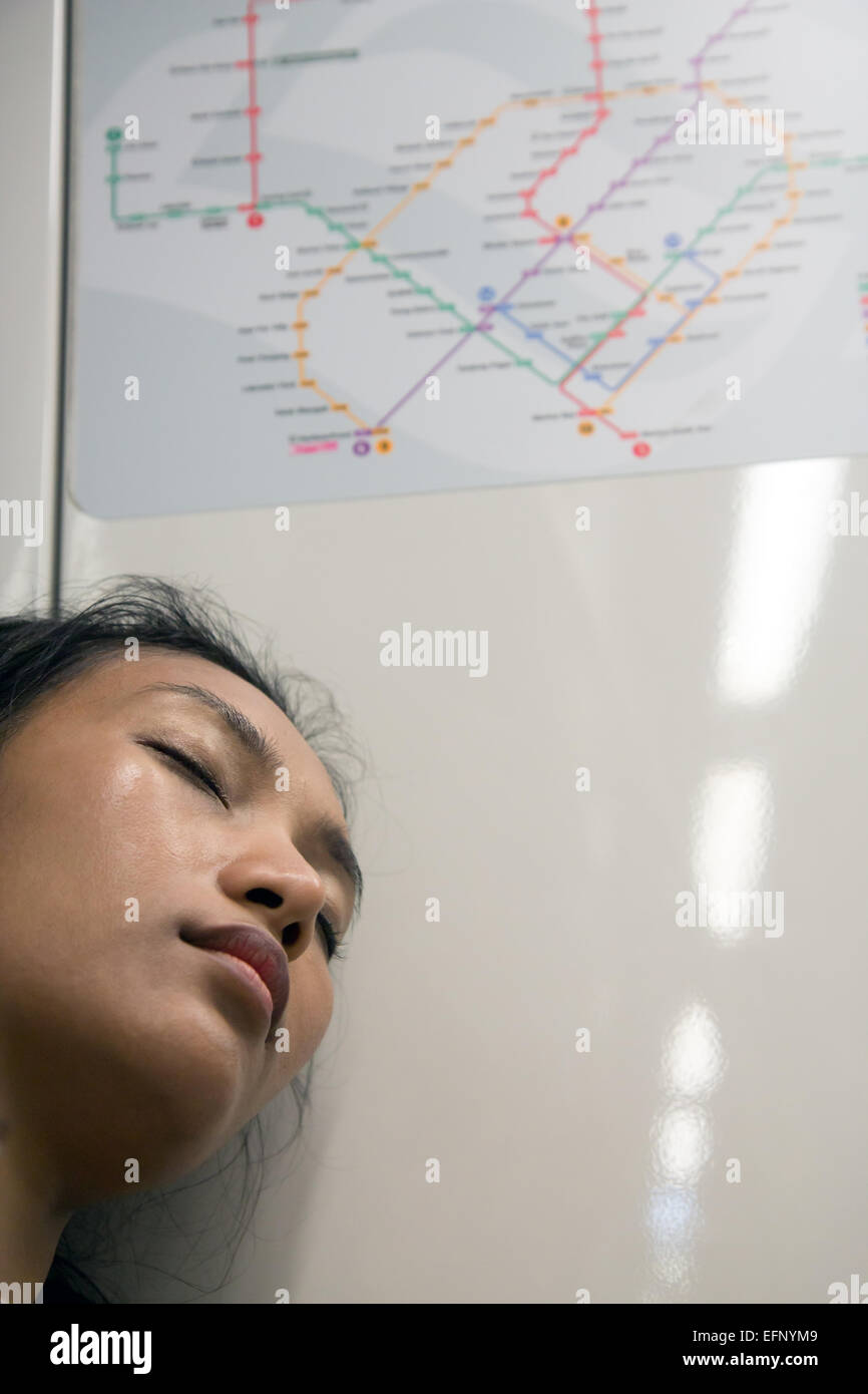 Frau schläft mit dem Zug unter der Karte des öffentlichen Verkehrs Stockfoto
