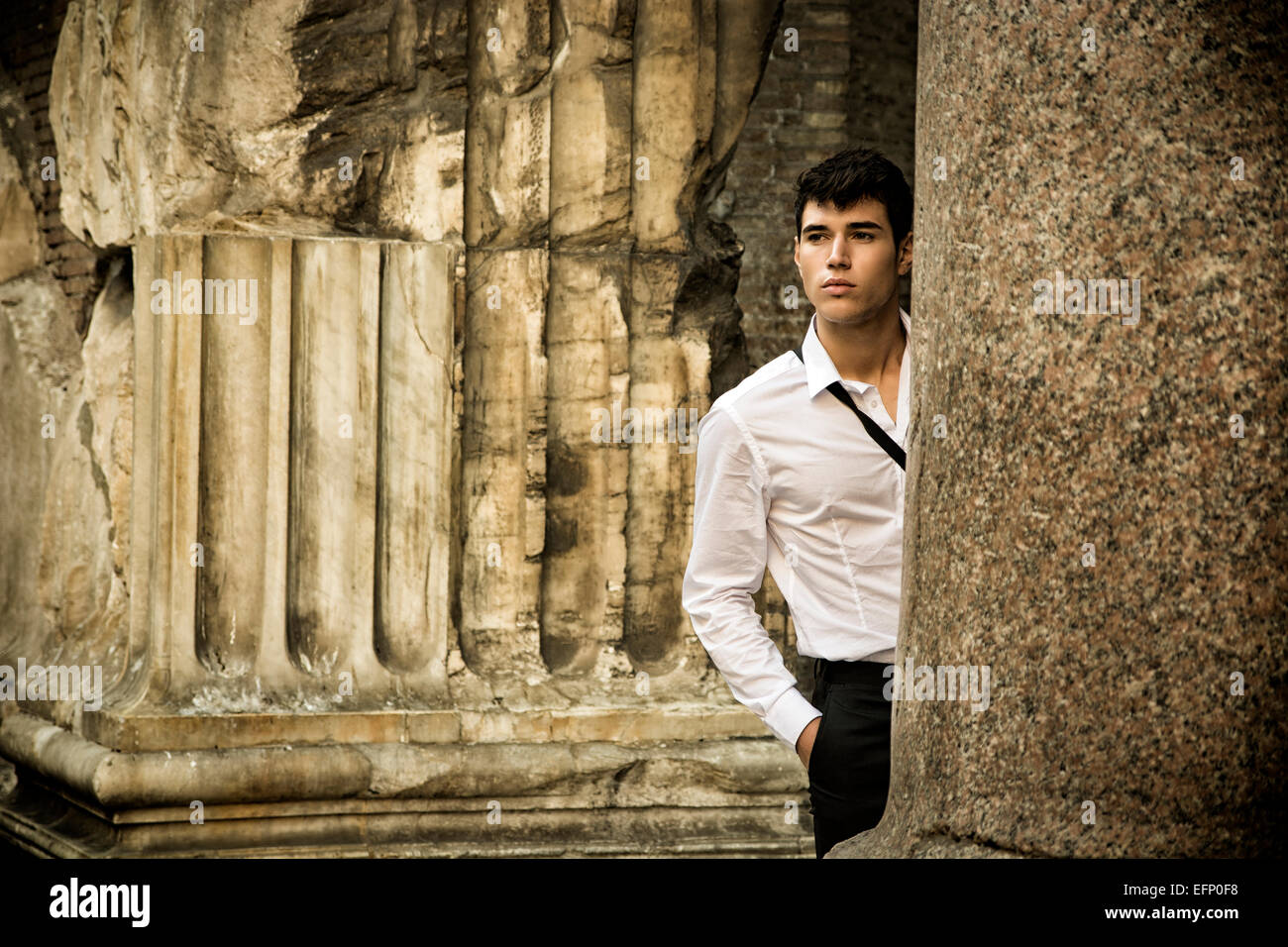 Hübscher junger Mann zwischen antiken Säulen aus Marmor Stockfoto
