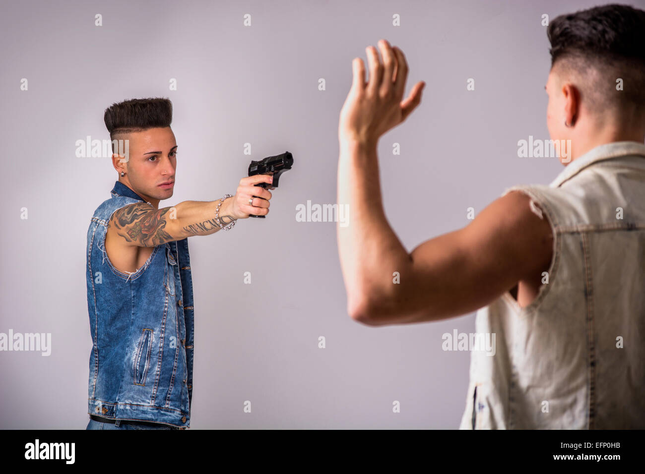 Junger Mann mit einer Pistole auf einen anderen Kerl Stockfoto