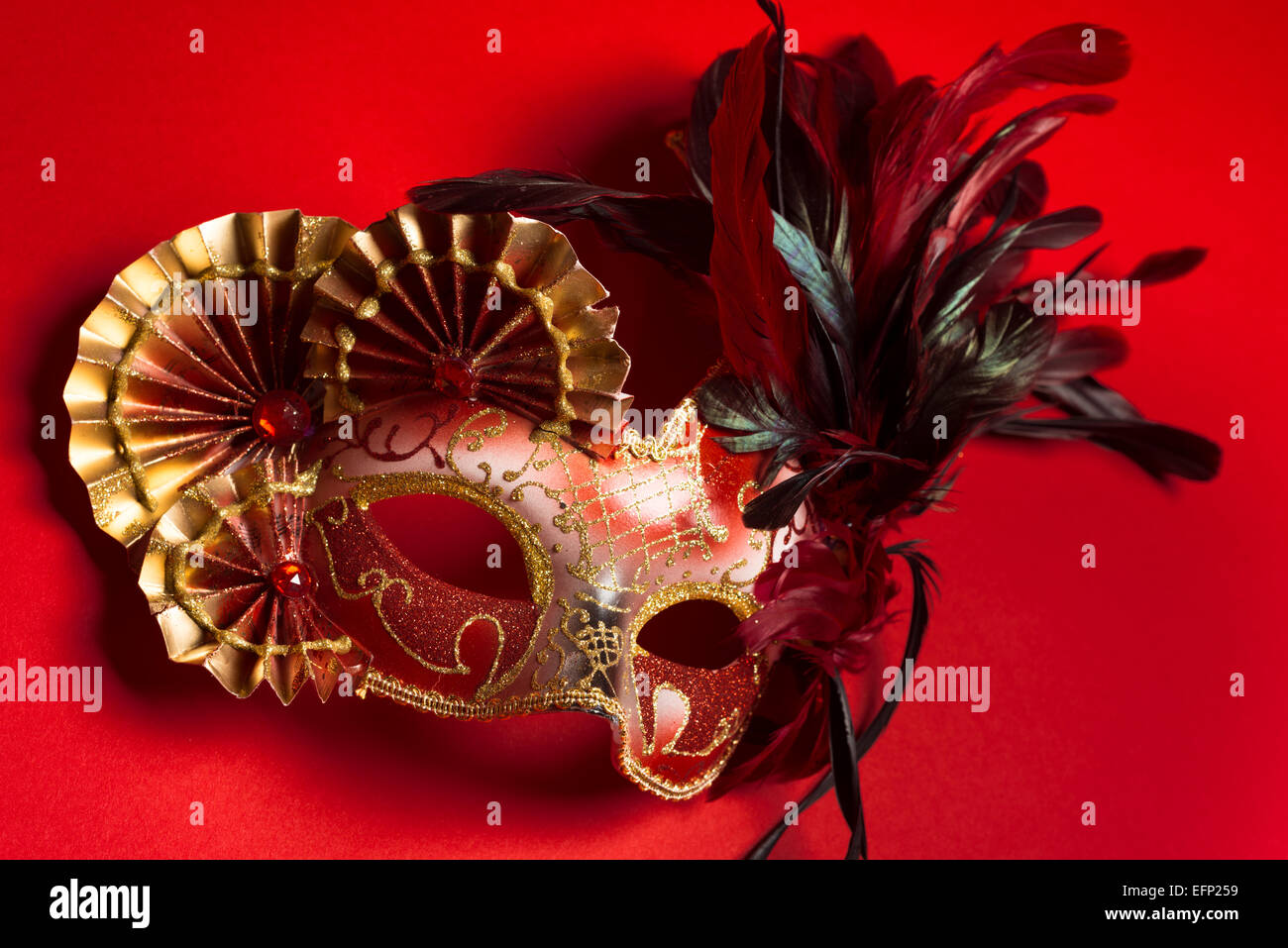 Eine rote und goldene venezianische, Karneval Maske auf rotem Grund Stockfoto