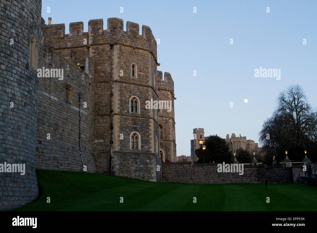 Henry VIII Gateway (von der Seite) und der Außenwand des Windsor Castle, Berkshire, England mit Mondaufgang in der Abenddämmerung im Januar Stockfoto