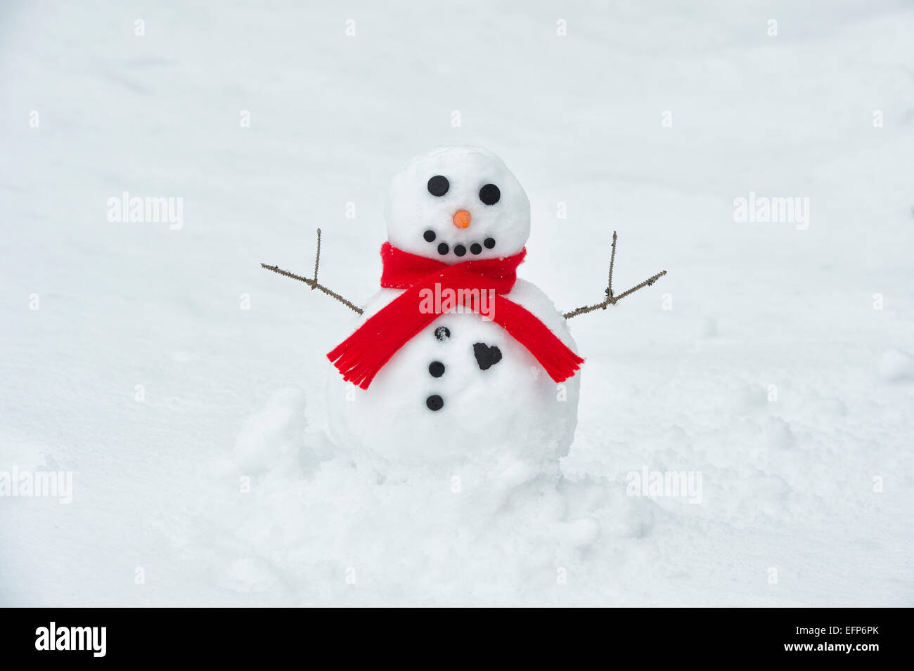 Glücklich Schneemann mit großen Kohle-Herz und rotem Schal Stockfoto