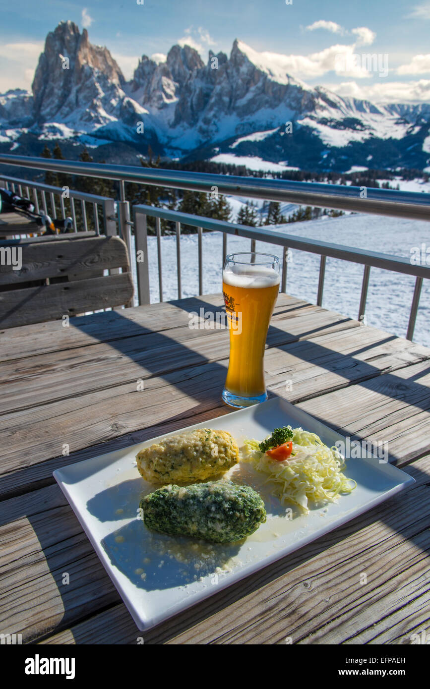 Traditionelle Canederli oder Knodel Teller serviert auf den Tisch mit Blick über die verschneiten Dolomiten, Alto Adige, Südtirol, Italien Stockfoto