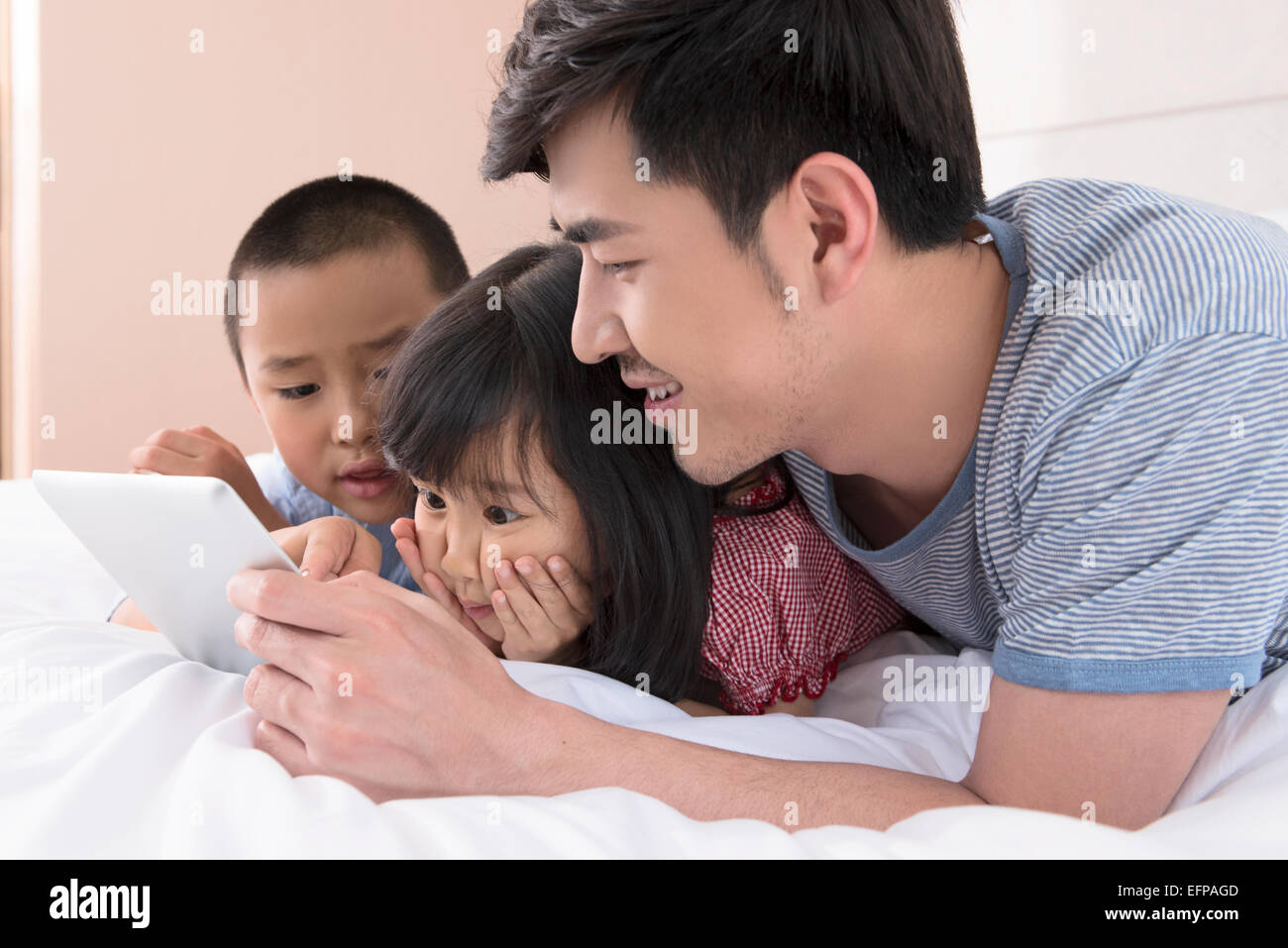Vater und Kinder mit Tablet im Bett Stockfoto