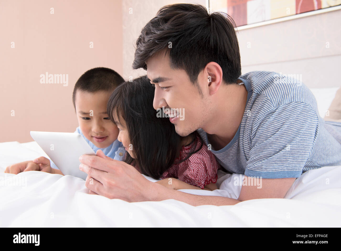 Vater und Kinder mit Tablet im Bett Stockfoto