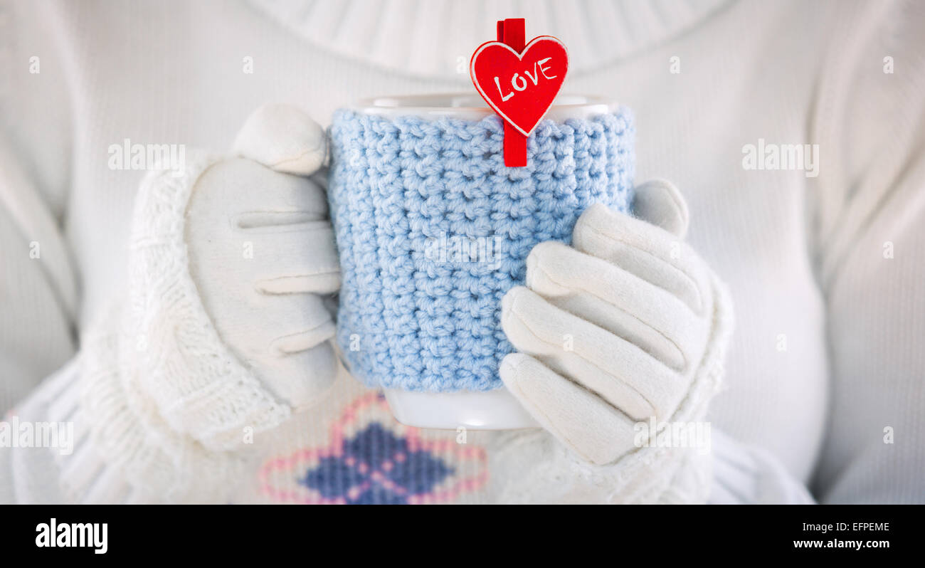Gestrickter Wolle-Cup in Menschenhand. Mit roten Herzen und das Wort Liebe. Valentines Day. Stockfoto