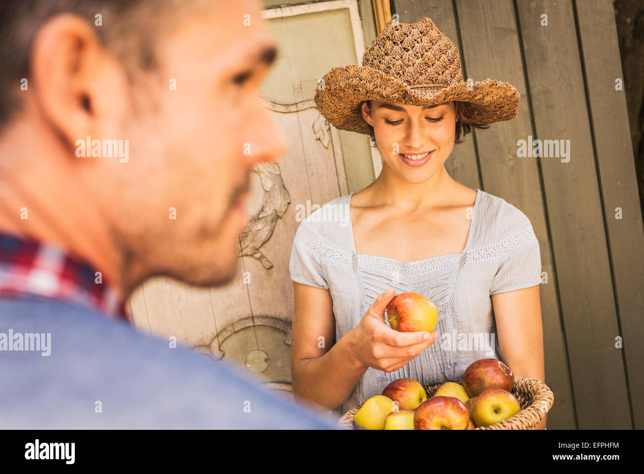 Jungen Frau mit Strohhut, hält Apfel aus Korb, Mitte erwachsenen Mannes in schehens Stockfoto