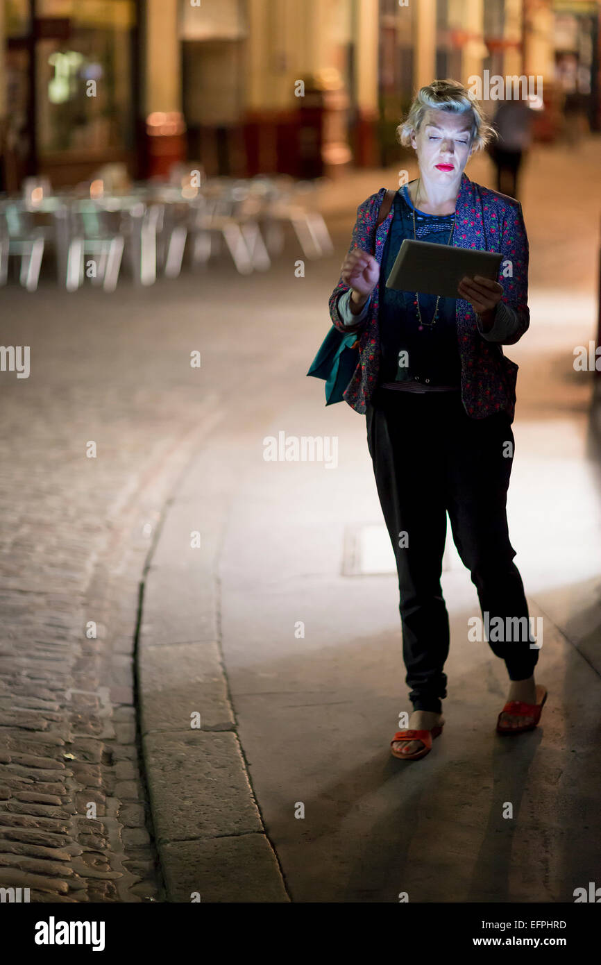 Reife Frau mit digital-Tablette auf der Straße in der Nacht, London, UK Stockfoto