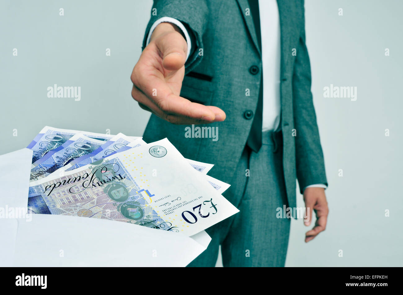ein Mann in Anzug nehmen einen Umschlag voller Pfund Sterling Rechnungen Stockfoto