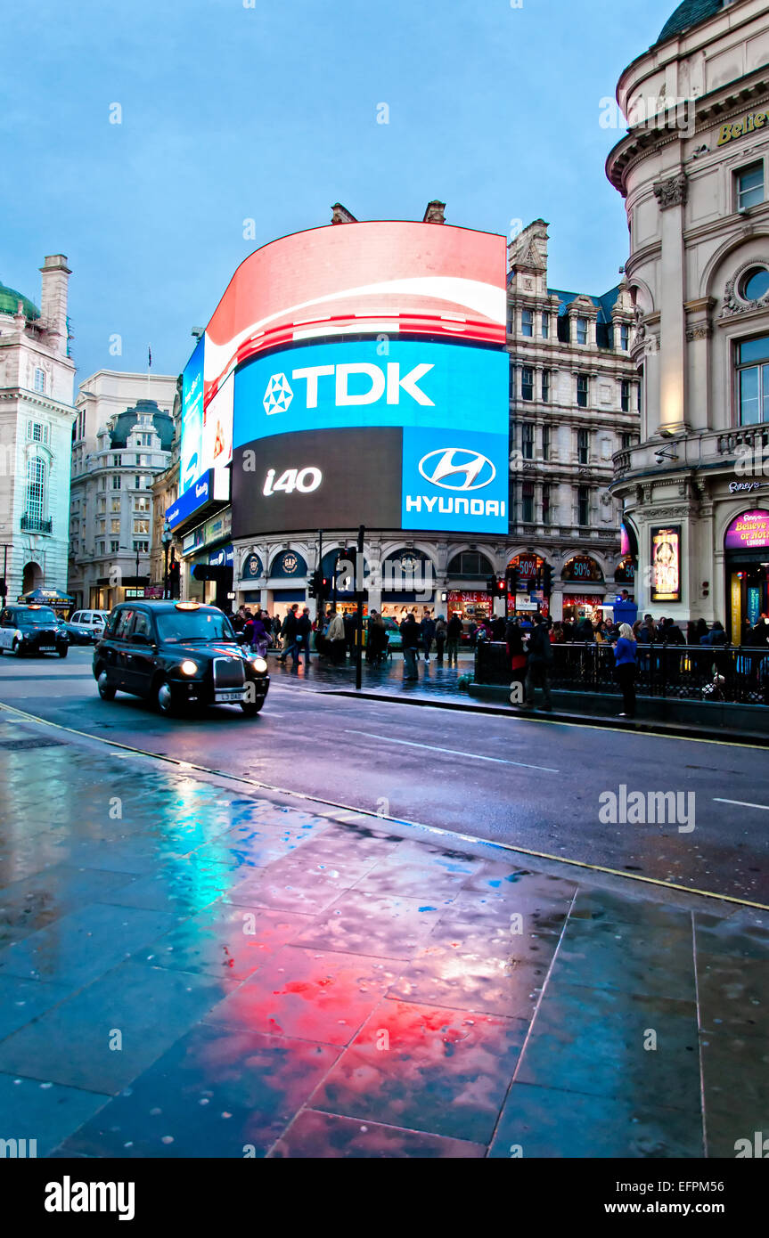 London, Vereinigtes Königreich - 12. April 2013: berühmten Piccadilly Circus Neon Schilder spiegelt sich auf der Straße mit dem Taxi in London, UK Stockfoto