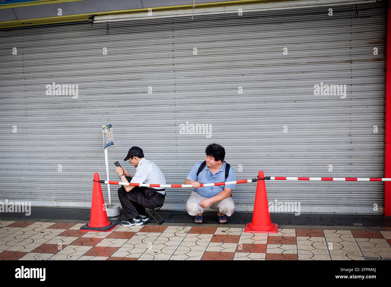 Zwei Personen bilden eine kurze Warteschlange in Osaka, Japan. Stockfoto