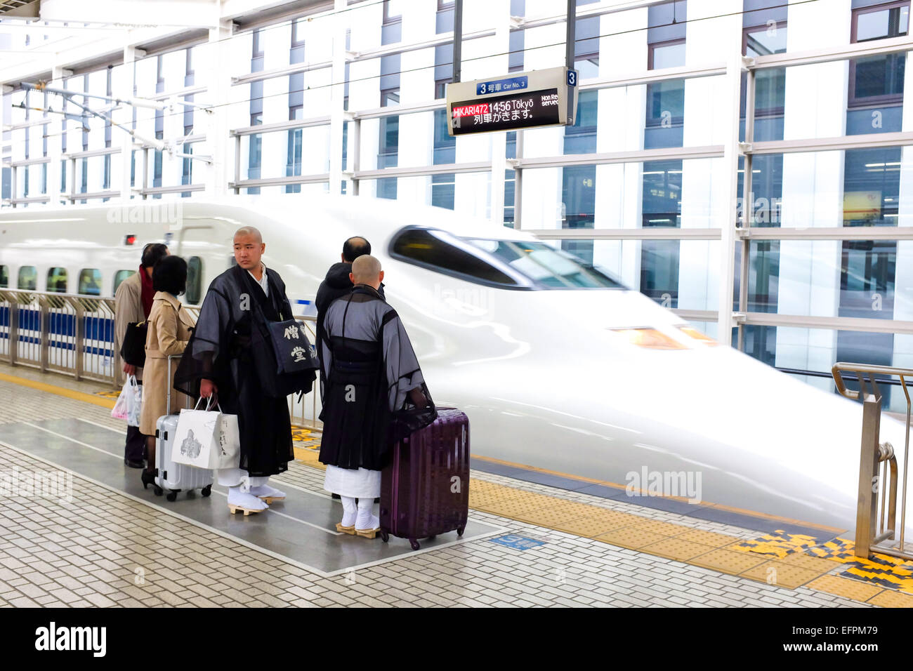 Zwei Mönche in Japan warten auf die Ankunft von einem Hochgeschwindigkeitszug. Stockfoto