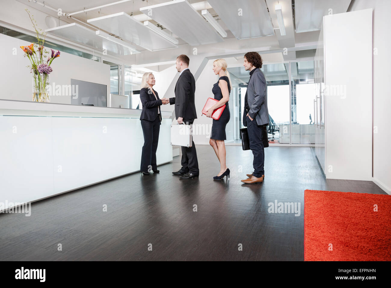 Frau Händeschütteln mit den Besuchern an der Rezeption Stockfoto
