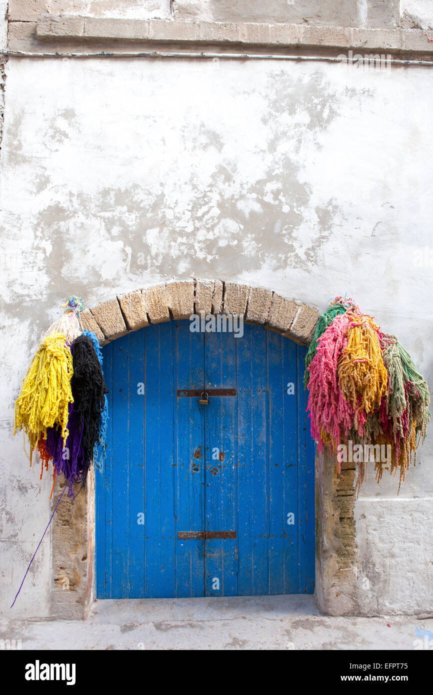 Die Trauben der gefärbten Wolle und blaue Tür, Essaouira, Marokko Stockfoto